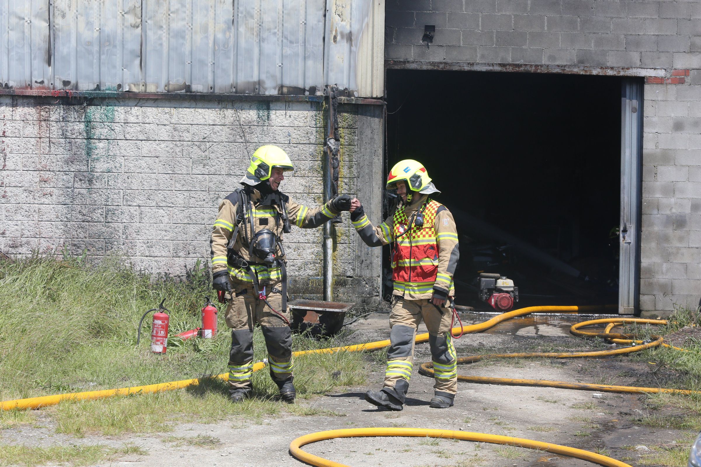 Dous bombeiros felic�tanse tras lograr apagar un incendio no pol�gomo industrial R�o do Pozo. 9/06/2021