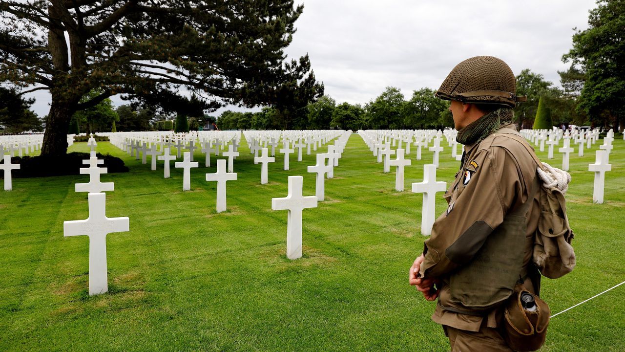 Un hombre que luce un uniforme militar estadounidense de época observa las tumbas en el cementerio galo de los soldados caídos estadounidenses en Colleville-Sur-Mer