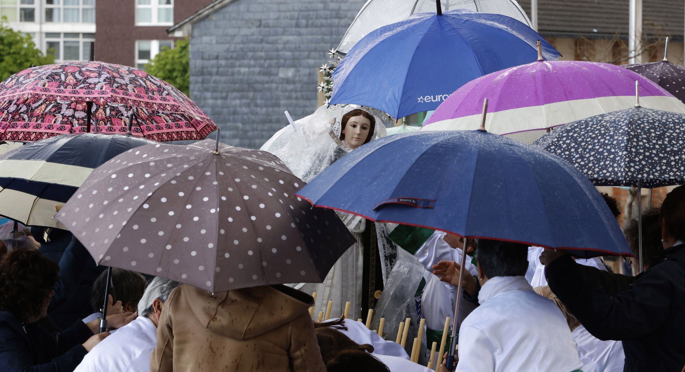 A Procesin da Esperanza de Burela  sorprendida por unha sarabiada, os devotos intentan protexer a imaxe cos seus paraugas. 19/04/2025