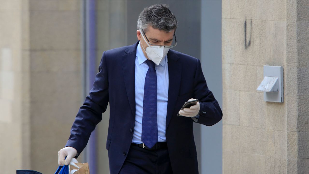 Un hombre mira su móvil en una calle de Lugo, donde las caras descubiertas empiezan a ser una excepción