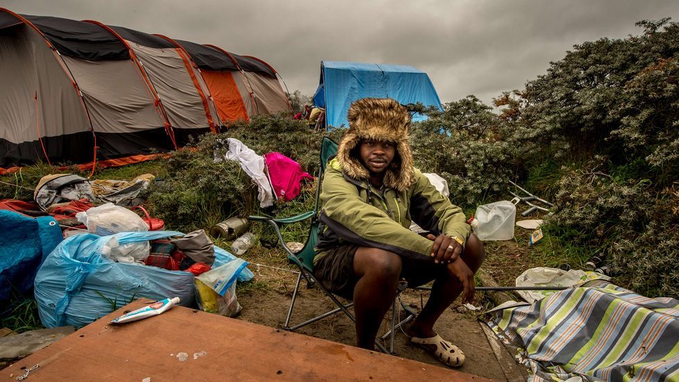 Un hombre sentado en una silla plegable en el campamento de inmigrantes de Calais, conocido como «Nueva Jungla», donde muchos tratan de llegar a Inglaterra.