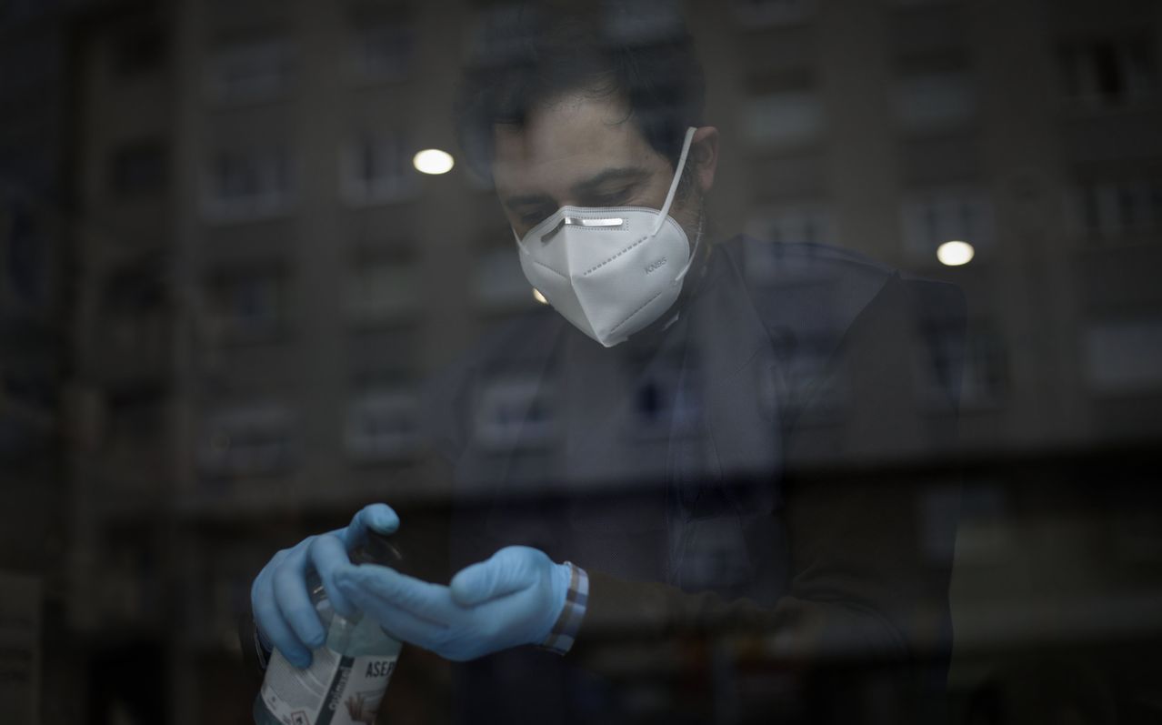  El farmac�utico Miguel Mosteiro de la Farmacia Laba�ou, desinfect�dose las manos para seguir atendiendo a trav�s de un simple ventanuco
