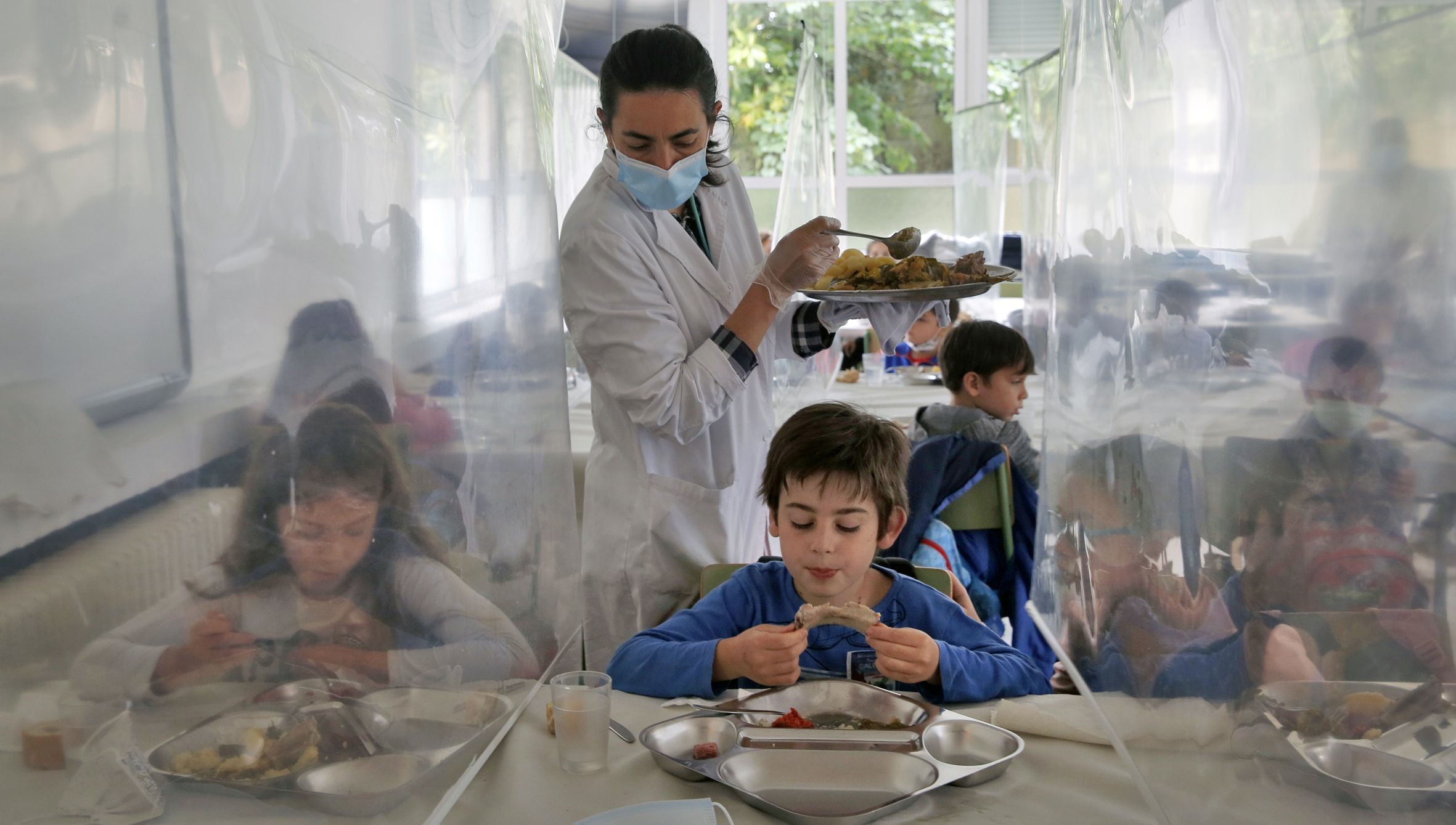 Unha auxiliar serve o xantar  a un alumno no comedor do CEIP Mosteiro en Meis. 14/05/2021