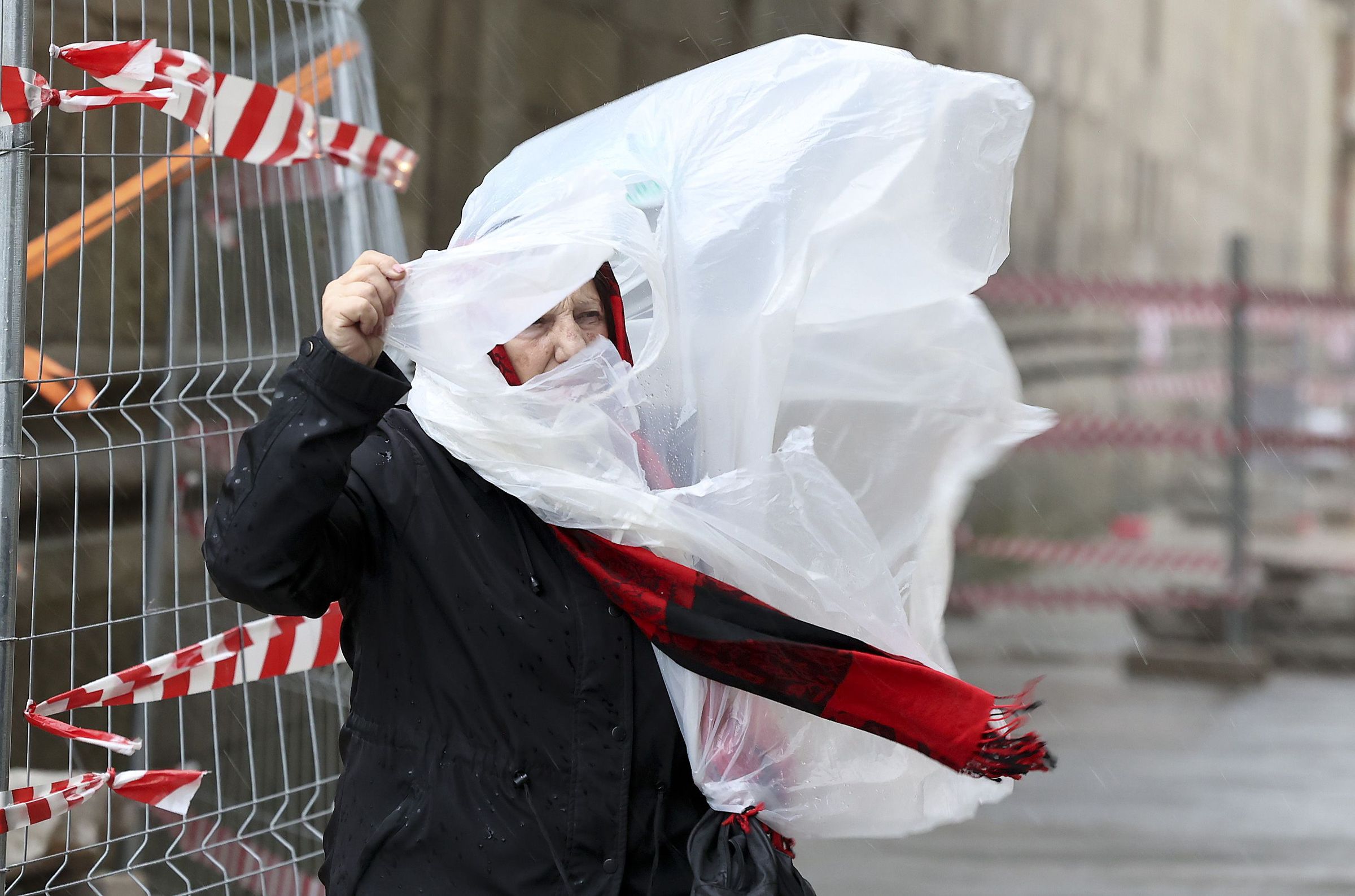 Unha muller loita co seu poncho fronte o vento e a choiva na entrada da Praza do Obradoiro. 24/11/2024