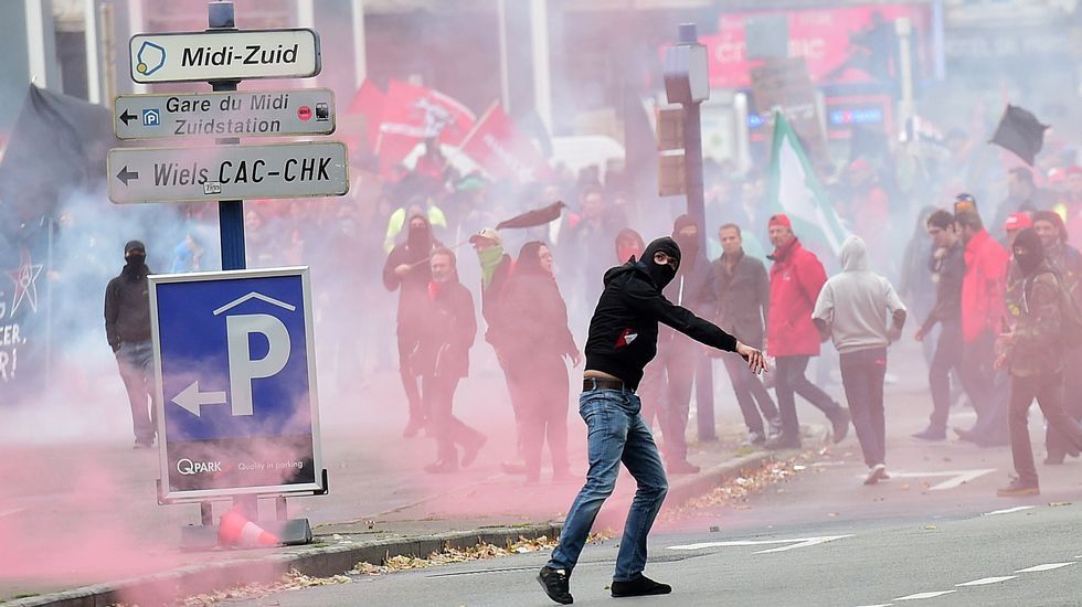 Un manifestante lanza un objeto durante los choques con la Policía en Bruselas, donde protestan por las medidas de austeridad del Gobierno.