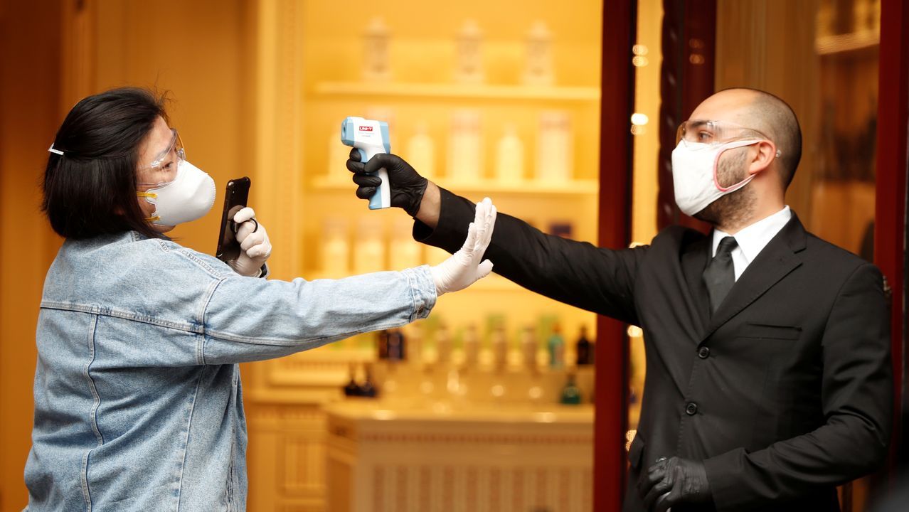 Un camarero, con guantes y mascarilla, sirve un café a un cliente, esta mañana en una plaza de Roma