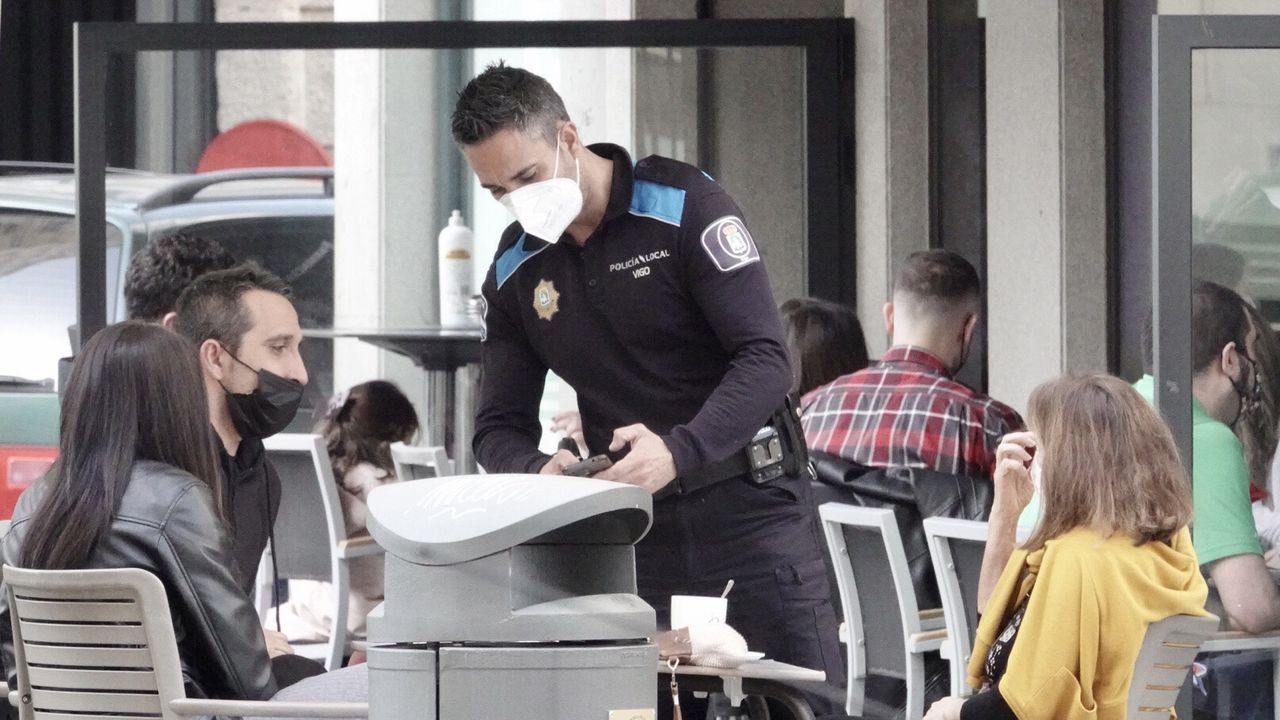 Un agente habla con dos clientes de un bar esta tarde en el Casco Vello vigués