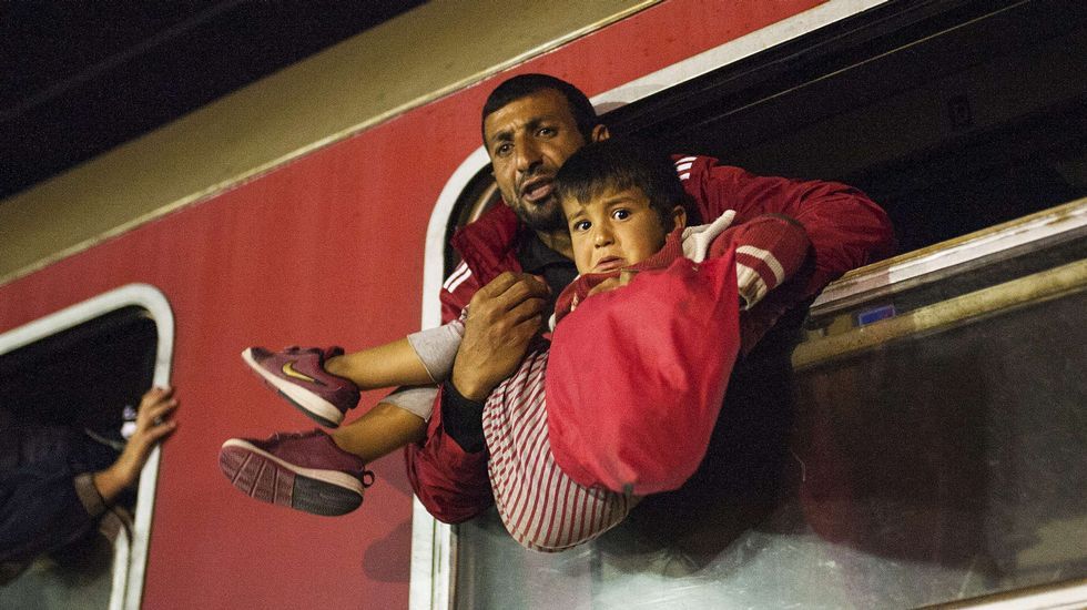 Un hombre sostiene a un niño en brazos de camino a Serbia.