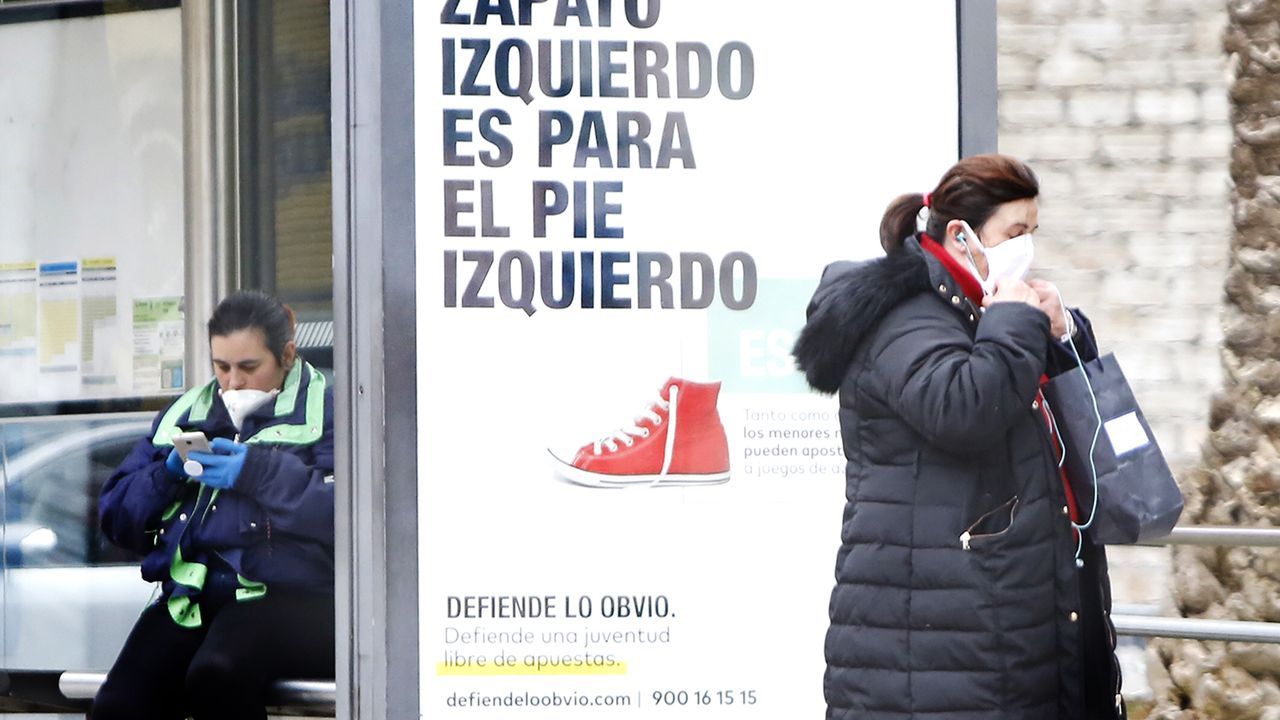 Con mascarillas esperando el autbús en Vigo