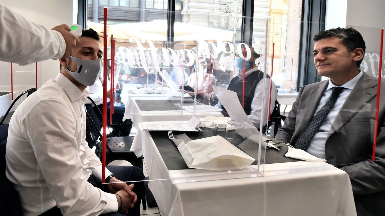 Un camarero le toma la temperatura a un cliente en un restaurante de Milán