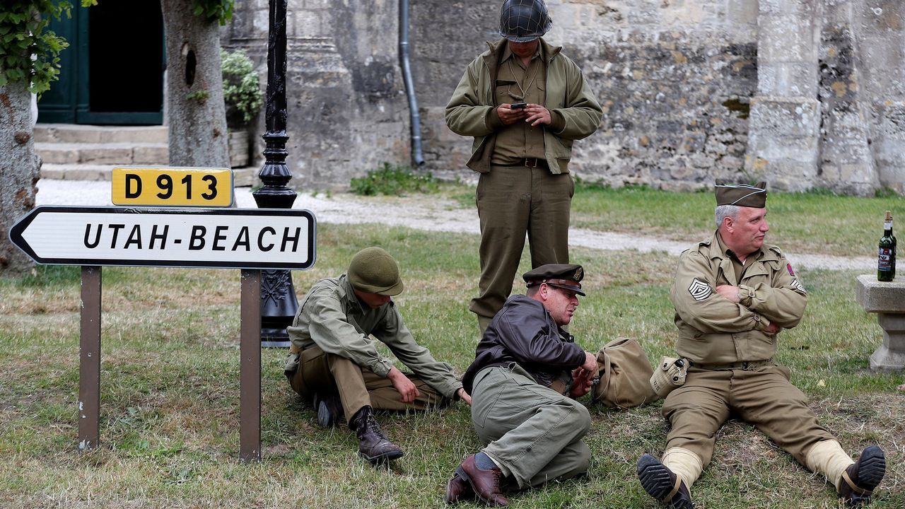 El veterano militar estadounidense George Shenkle conversa con varios jóvenes en el cementerio de los soldados caídos estadounidenses en Colleville-Sur-Mer