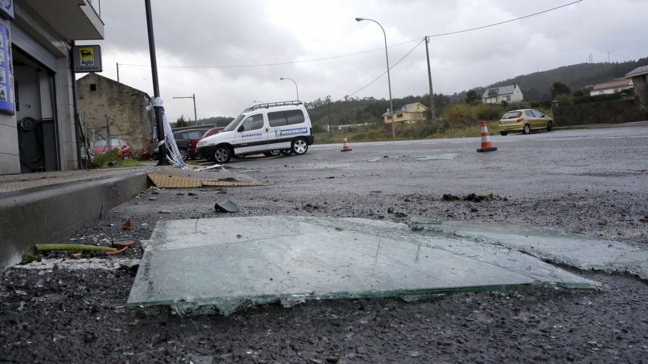 .Cristales caídos de una terraza de un piso de Arteixo y los destrozos en varios coches