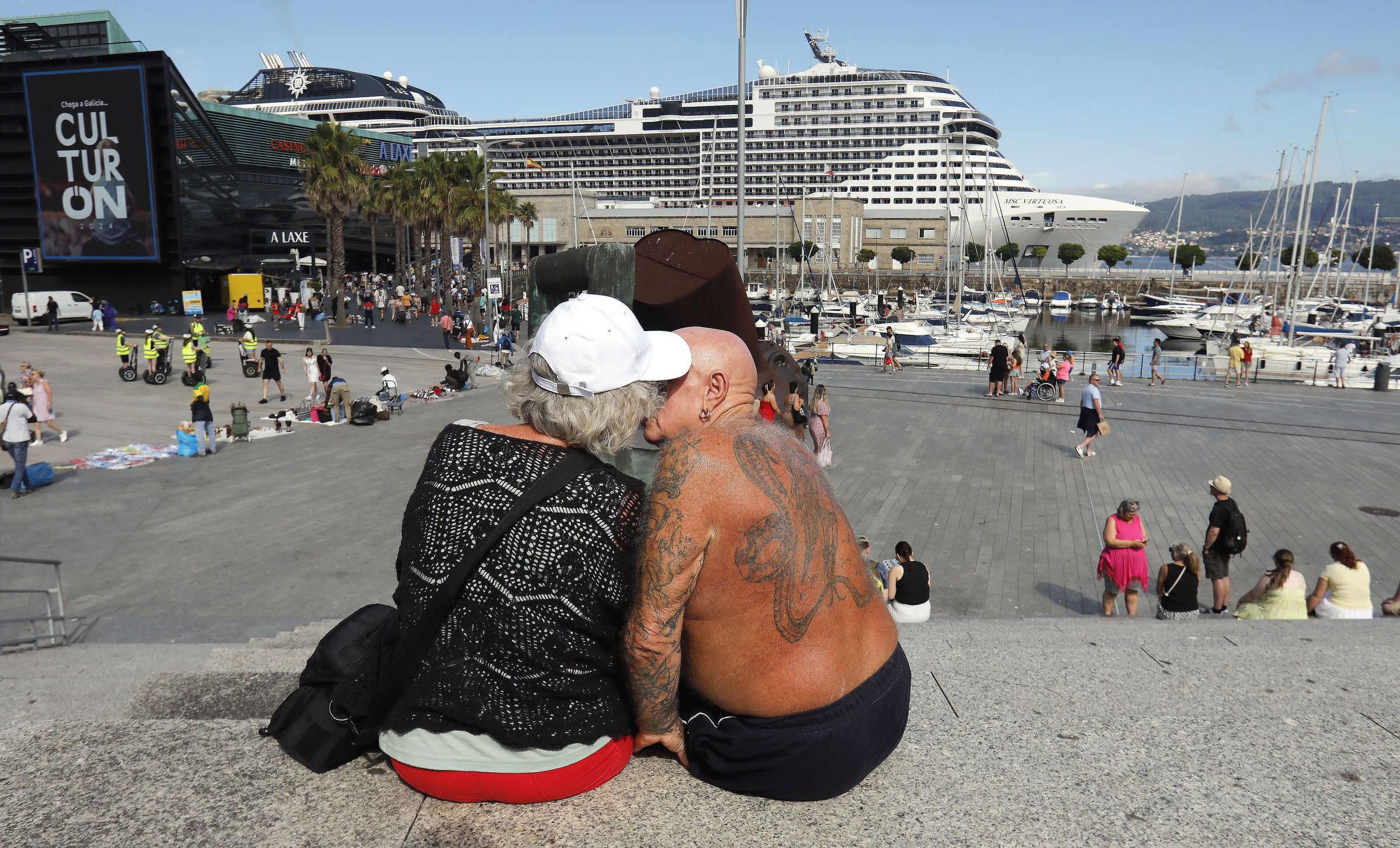 Parella de turistas co cruceiro MSC Virtuosa bicndose no porto de Vigo. 12/08/2024