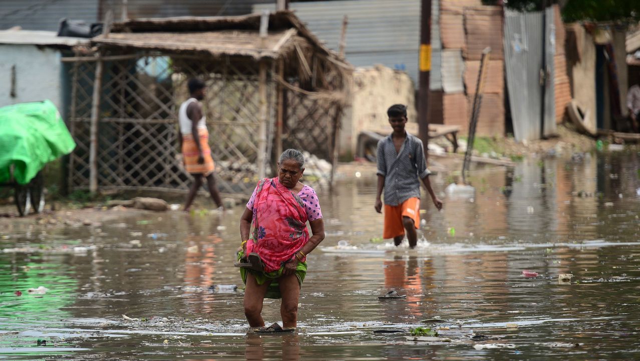 Vecinos de una barriada de Allahabad, en India, caminan por una calle inundada