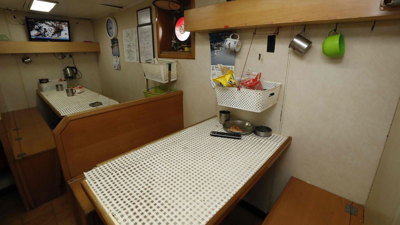 Televisión, con conexión por satélite, y dos mesas en el comedor del barco