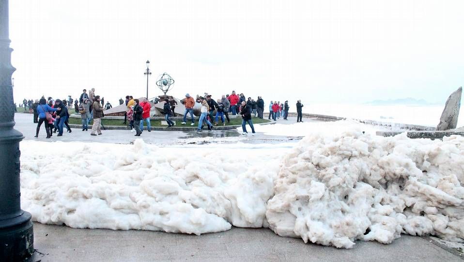 La espuma del mar cubre el centro de Baiona ante la sorpresa de los peatones