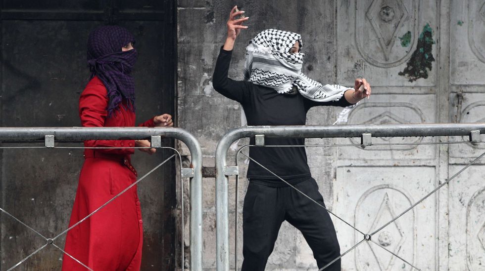 Una joven mujer palestina lanza piedras contra las fuerzas de seguridad israelíes en Hebrón.