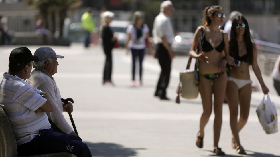 Dos jóvenes en biquini caminan por el paseo marítimo de A Coruña