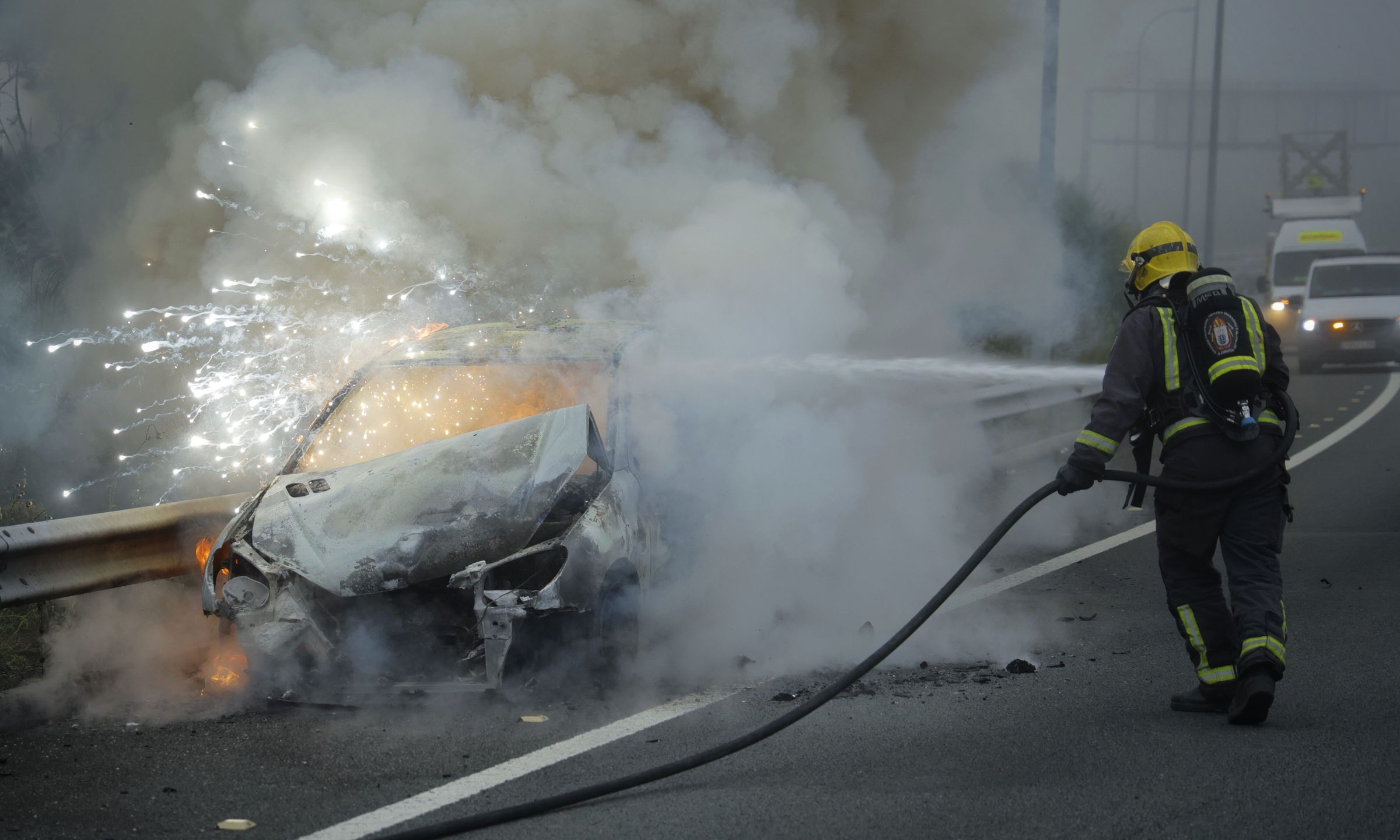 Un bombeiro sofoca as chamas dun coche incendiado na terceira ronda, direccin entrada a Corua. 20/06/2025