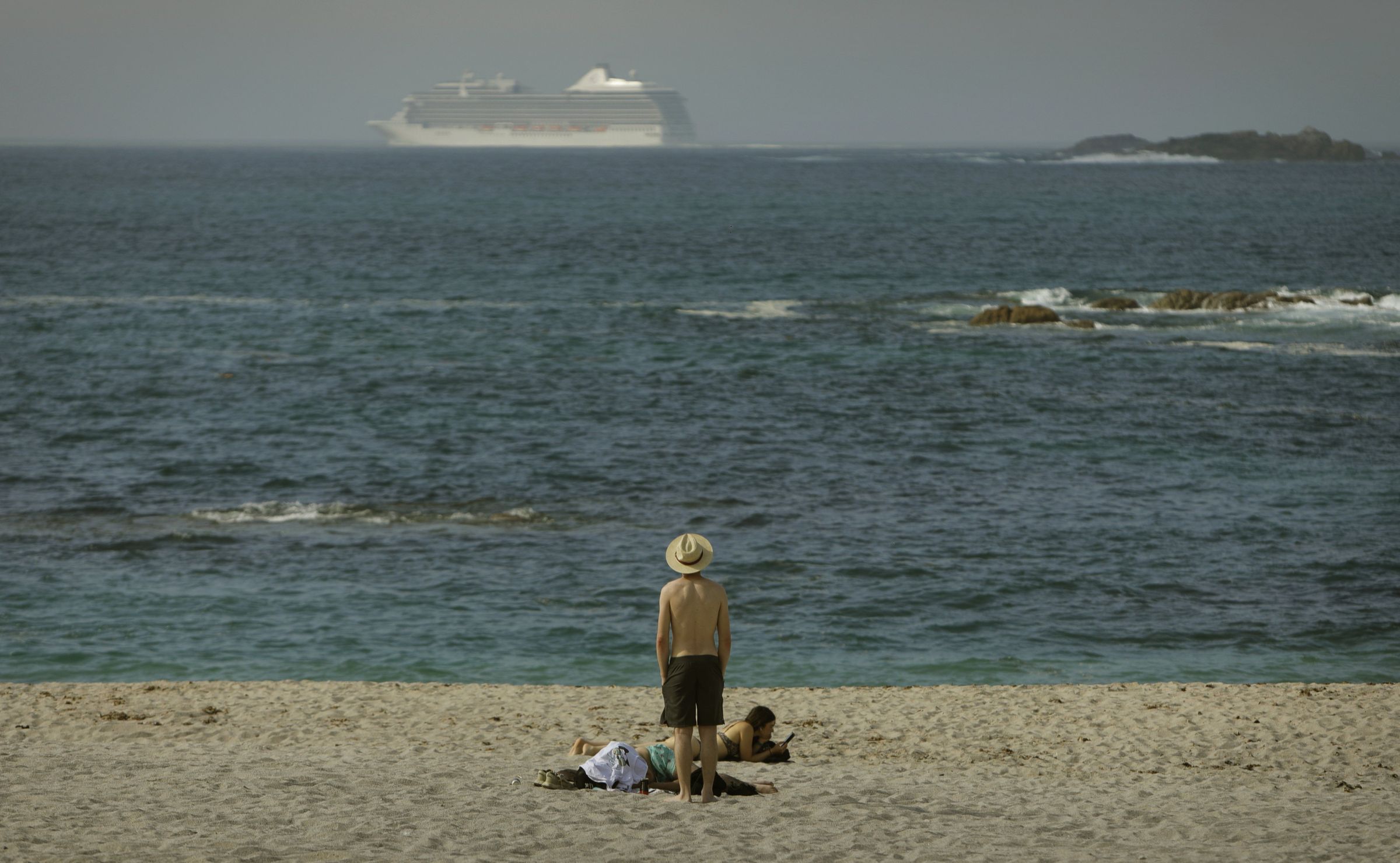 Un ba�ista�na praia de Riazor contempla un trasatl�ntico despois de partir de A Coru�a. 29/05/2023