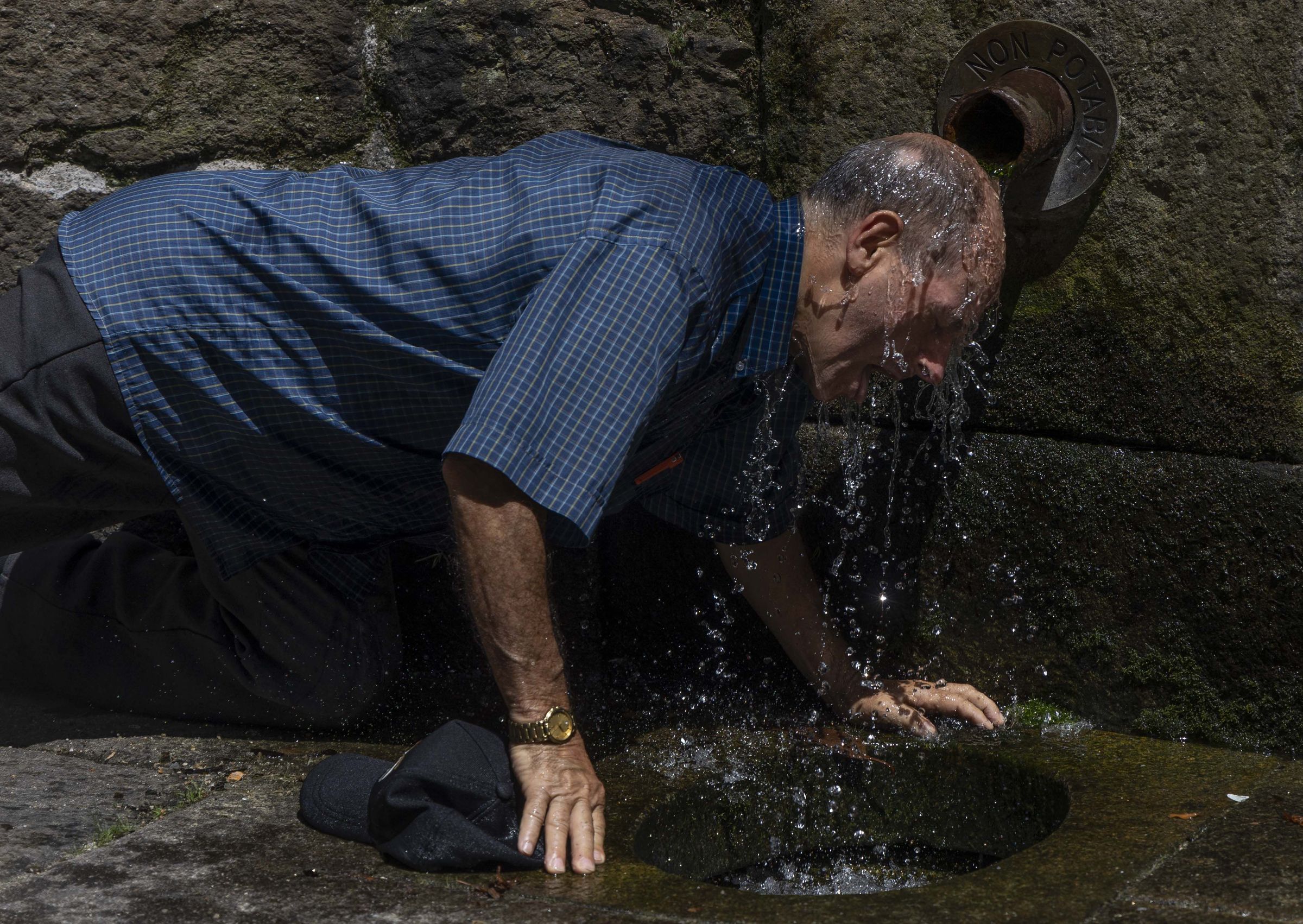 Un home refrscase na Fonte Sequelo de Santiago en plena ola de calor. 04/07/2025