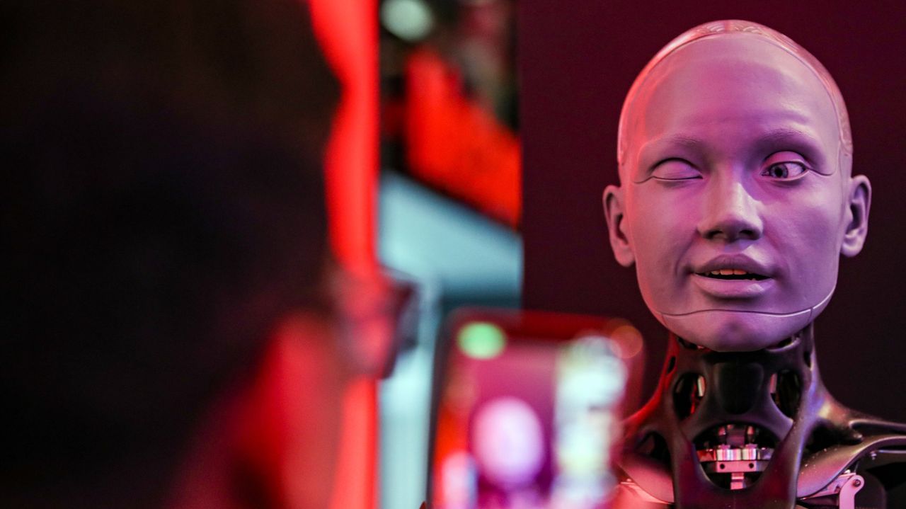 El robot con forma humanoide m�s avanzado del mundo, 'Ameca' (R), hace un gui�o a un visitante durante una feria tecnol�gica.