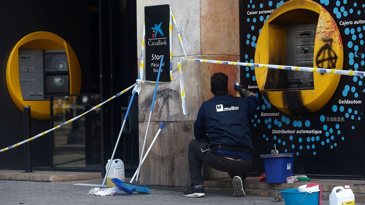 Un operario intenta arreglar los daños causados en una oficina bancaria durante los disturbios en Barcelona