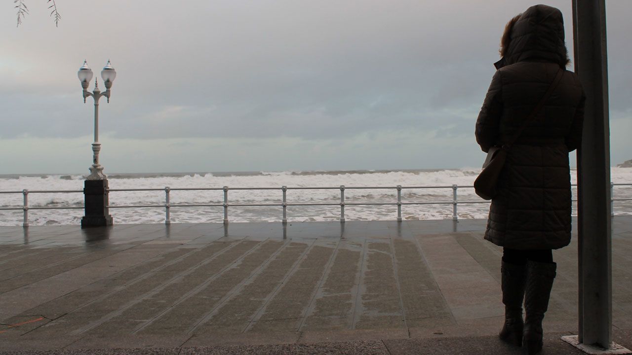 Oficialidad del asturiano.Una mujer observa un temporal en el paseo del Muro de Gij�n