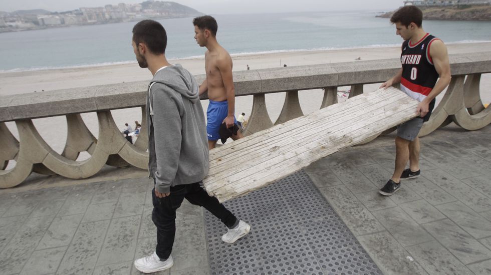Jóvenes en el arenal del Orzán carretando madera