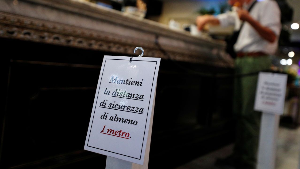Un camarero, con guantes y mascarilla, sirve un café a un cliente, esta mañana en una plaza de Roma