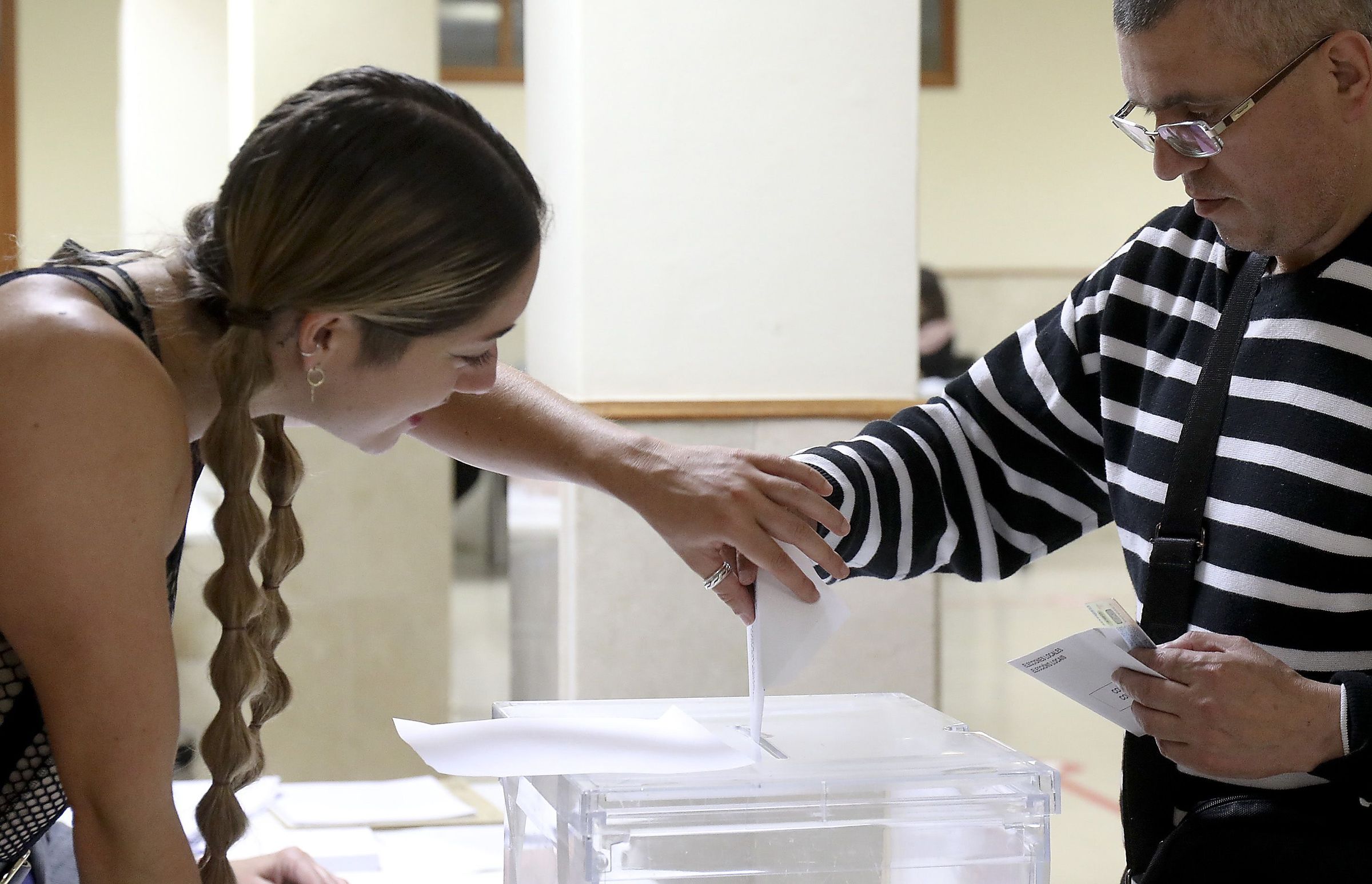 A presidenta de unha mesa electoral axuda a un votante a meter o seu sobre na urna durante a xornada do 28M. 28/05/2023