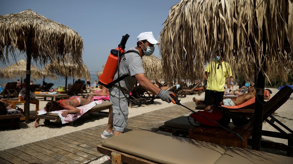 Un hombre desinfectando las hamacas en Atenas, donde han reabierto las playas
