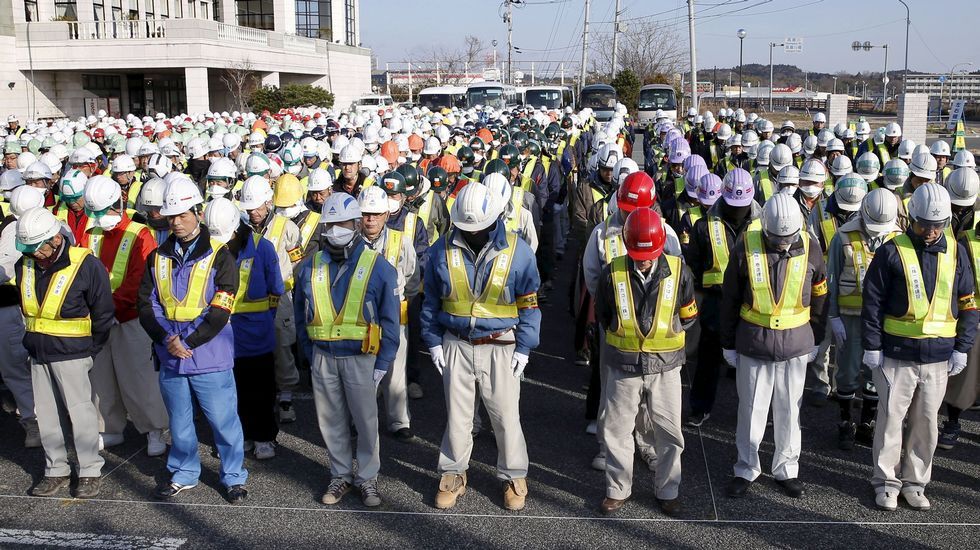 Operarios que trabajan en las labores de descontaminación de la zona, guardan un minuto de silencio.