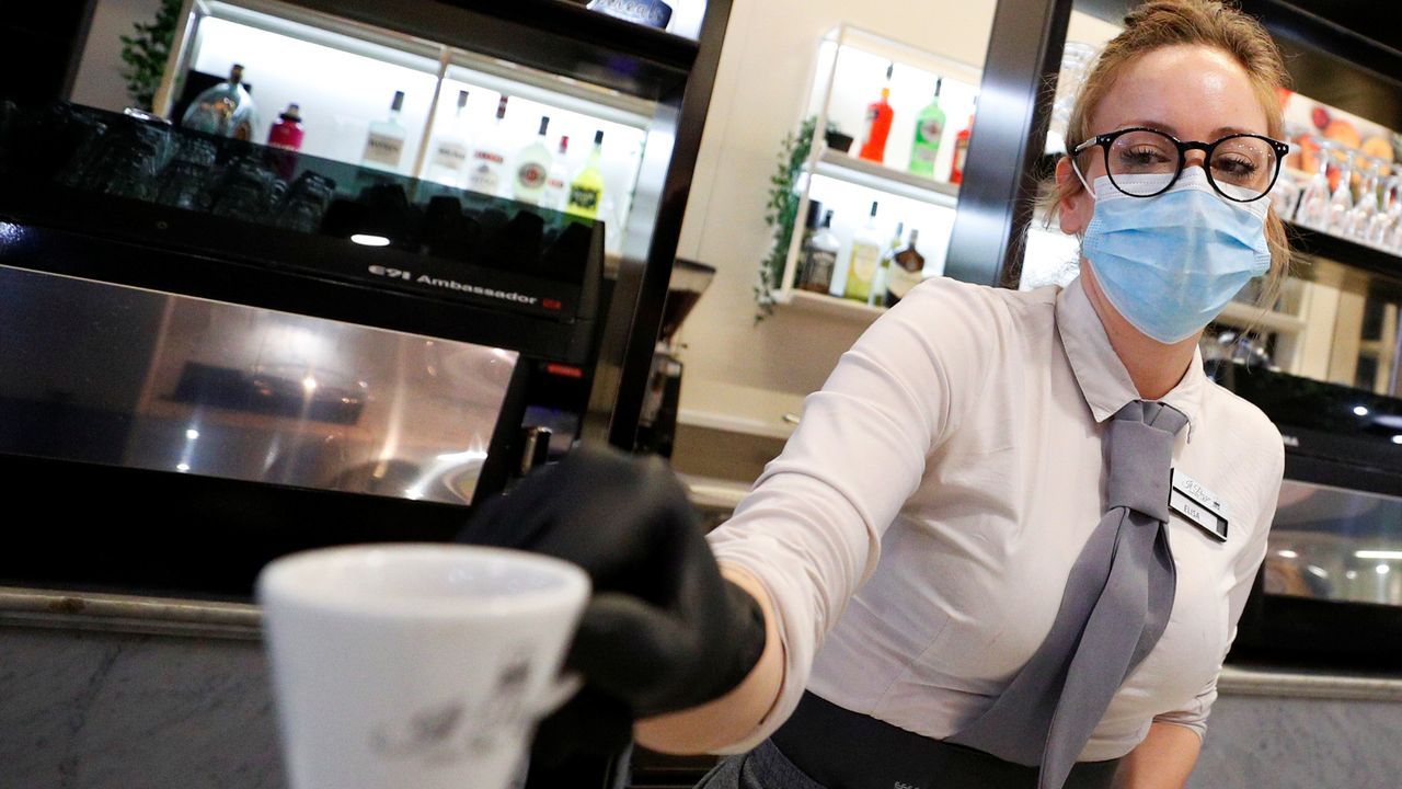 Un camarero, con guantes y mascarilla, sirve un café a un cliente, esta mañana en una plaza de Roma