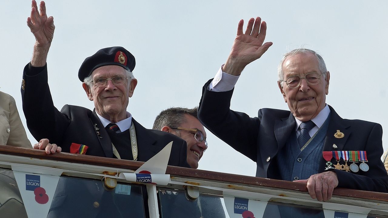 Veteranos británicos de la Segunda Guerra Mundial saludan a su llegada a bordo del barco MV Boudicca al Puerto de Poole