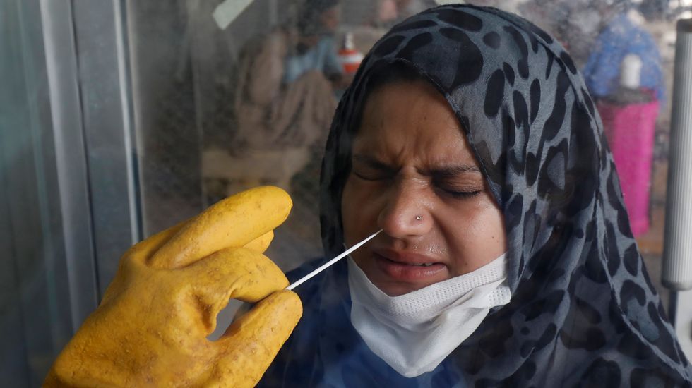 Un paramedico realizándole un test a una mujer paquistaní