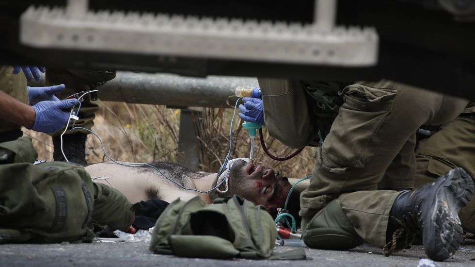 Soldados israelíes tratan a un palestino vendado después de que miembros infiltrados de las fuerzas de seguridad hebreas le dispararan.