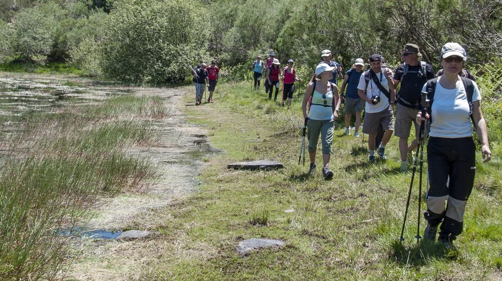 Miembros del club Senderismo Morrazo caminando por la orilla de la laguna