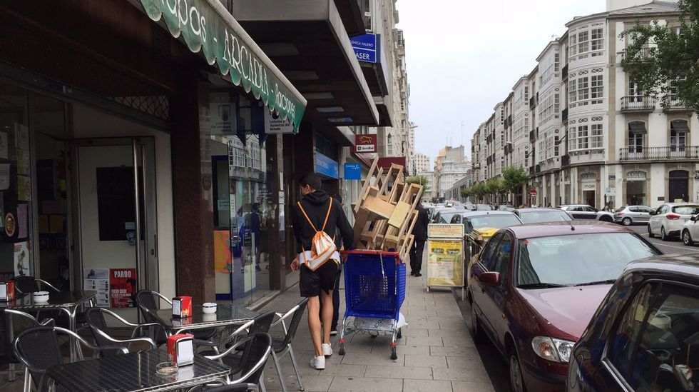 Jóvenes trasladando madera en carritos de la compra en la plaza de Ourense