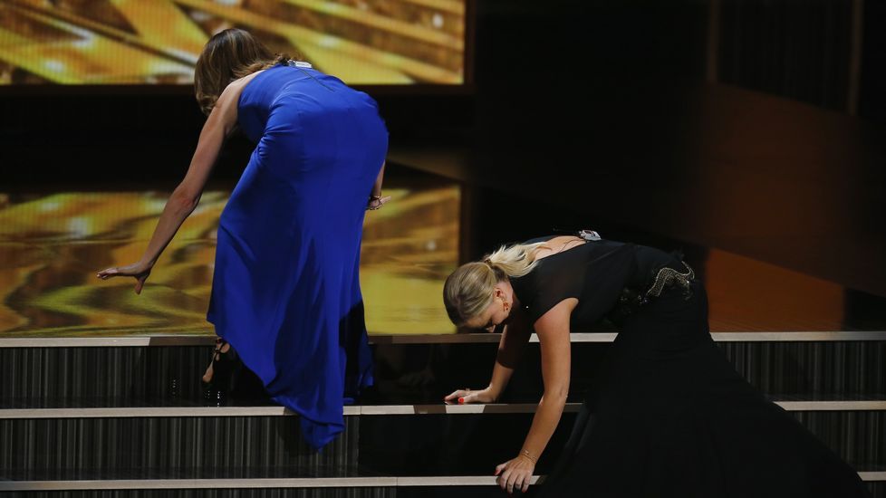 Los vestidos de infarto, los tacones de vértigo y los nervios y emoción a la hora de recoger su premio hicieron que las actrices Amy Poehler y Tina Fey trastabillearan al subir algunos escalones, camino del escenario durante la gala de los premios Emmy en el año 2013.