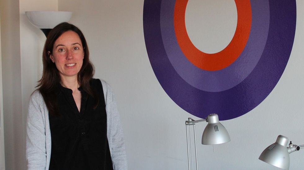 Laura Viñuela, en su despacho, junto a logo de Espora, su empresa