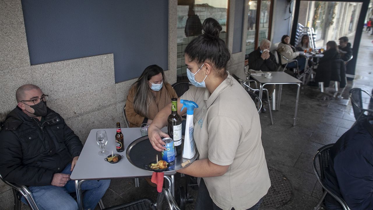 Una camarera atiende la terraza en el primer día de cierre perimetral en Boiro