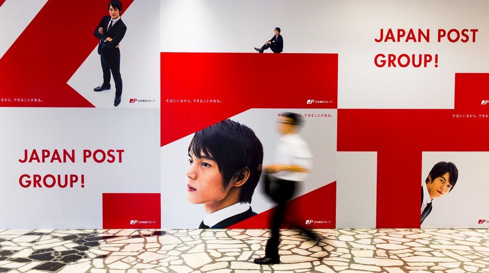 Un hombre camina al lado de un anuncio en las oficinas centrales de Japan Post.