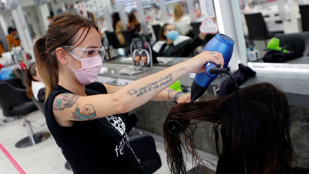 Un camarero, con guantes y mascarilla, sirve un café a un cliente, esta mañana en una plaza de Roma