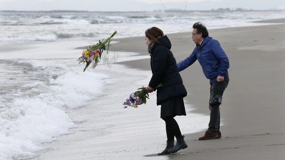 Mark Kanekita y Sadakuni Ito lanzan flores al mar en memoria de las víctimas.